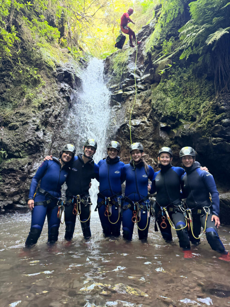 Canyoning in Madeira, A Practical Guide 5 A group of canyoneers cheers in shallow waters as their instructor abseils a waterfall in Porto Novo, Camacha, during a Begginner Level 1 canyoning tour with Go Explore Madeira.