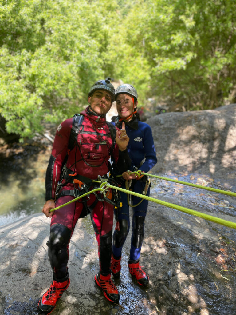 Best canyoning experiences in Madeira 5 Two canyoneers stand secured on a rocky ledge in Ribeira do Cidrão, Nuns Valley, preparing their ropes for an Intermediate Level 2 canyoning experience with Go Explore Madeira.