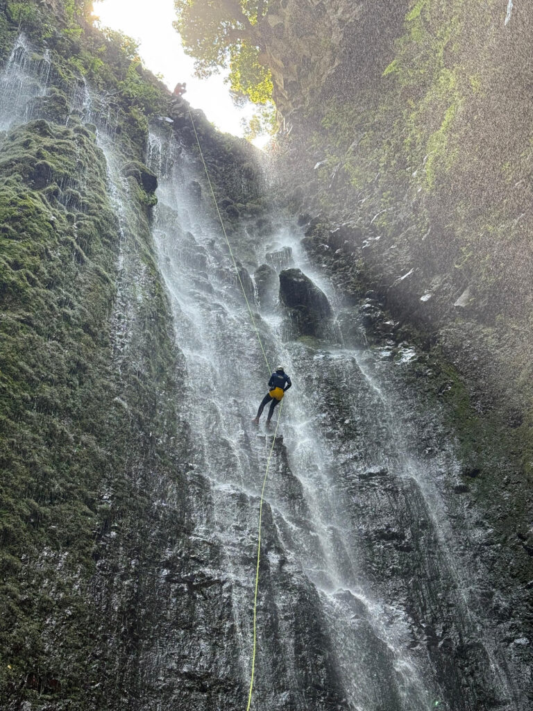 Best canyoning experiences in Madeira 3 A canyoneer abseils down a towering sunlit waterfall in Ribeira Funda Inferior Inferior during an Advanced Level 3 canyoning experience with Go Explore Madeira.