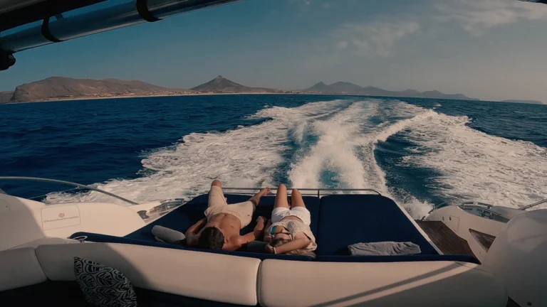 A couple sunbathing next o each other on the back of aa Luxury Madeira Yacht Charter Rental in the sea of Madeira enjoying the view of the PortoSanto syline, an experience by Luxury Charter Madeira.