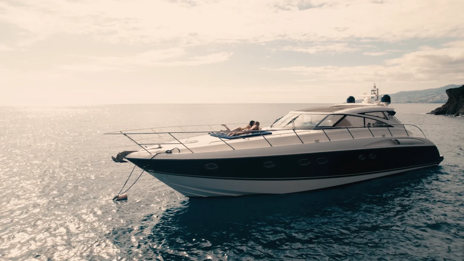 Luxury Madeira Yacht Charter Rental in the sea with two woman sunbathing, near the coast of Madeira, an experience by Luxury Charter Madeira.