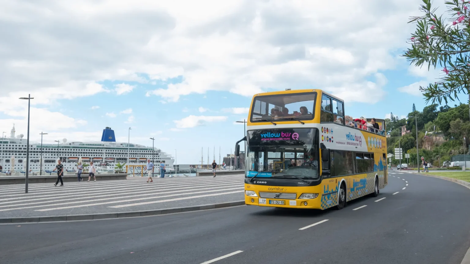 An Hop-on Hop-off Bus near Funchal marina with a cruise ship on the back, an experience by Carristur.