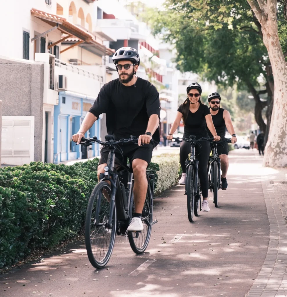 Group of three riders pedaling e-bikes along a shaded city cycle path in , an experience by MADcycle.