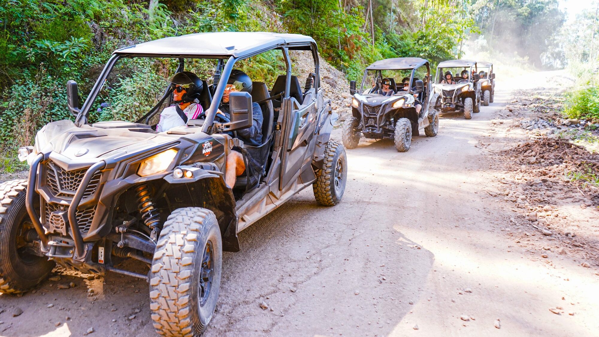 Which Buggy Tour in Madeira Is Right for You 3 Buggy Tour Riding at Campanário with a line of off-road buggies driving along a dusty forest track, guests wearing helmets and enjoying the Madeira mountain scenery, during an experience by Buggy Funtrip Madeira.