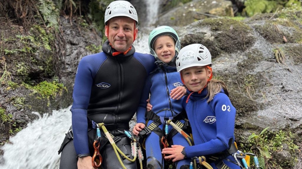 Canyoning in Madeira, A Practical Guide 3 A father sits with his two children on rocks beside a fern-lined waterfall in Porto Novo, Camacha, during a Beginner Level 1 canyoning tour with Go Explore Madeira.