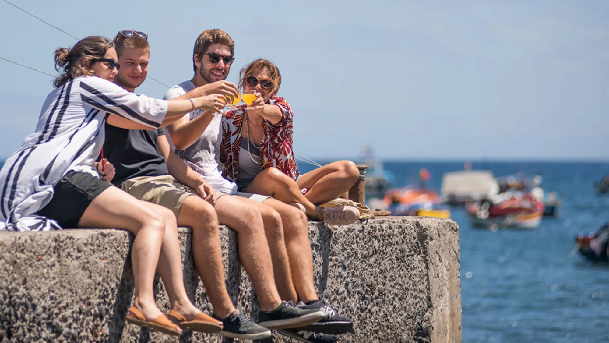 Canyoning in Madeira, A Practical Guide 8 Friends toasting poncha drinks while relaxing by the sea during the Bar hopping and Poncha Workshop, an experience by Wine Tours Madeira.