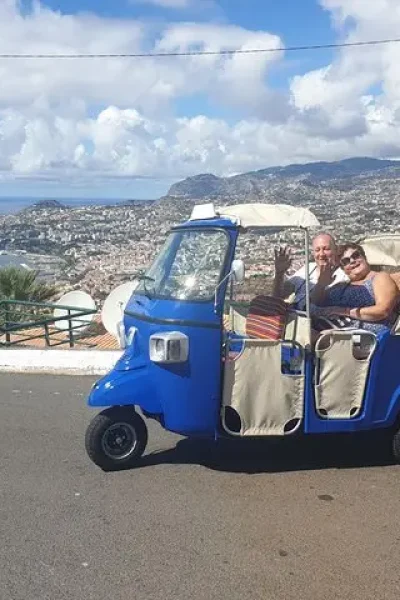 Blue tuk tuk parked at a viewpoint above Funchal bay with the city and coastline behind
