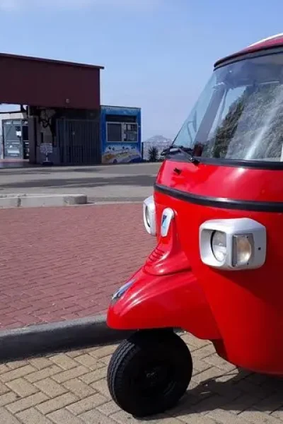 Red Tuktuking tuk tuk parked in Funchal, showing its open sides and striped seating