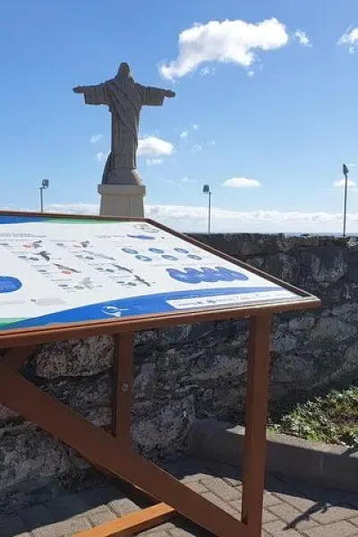 Interpretive sign about Madeira's marine protected areas at the Christ the King viewpoint, with the statue and the ocean behind