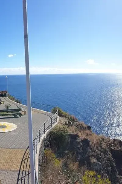 The Christ the King statue on its clifftop terrace at Garajau, with benches, a paved viewpoint and the Atlantic beyond