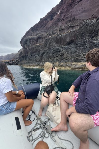 Three friends on an Luxury Yacht Charter to Desertas photograph towering red volcanic cliffs over calm waters under overcast skies, an experience by Luxury Charter Madeira.