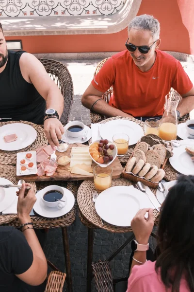 Group enjoying a relaxed late breakfast with fresh bread, fruit, cheese and coffee at Quinta do Saraiva during an E-Bike Road Tour, an experience by MADcycle.