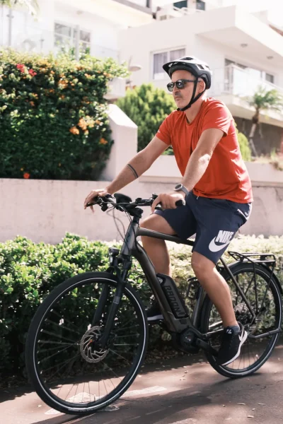 Rider pedaling an e-bike along a sunny city path in funchal surrounded by greenery during the E-Bike Road Tour, an experience by MADcycle.