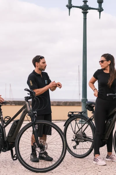 Group of riders with their e-bikes gathered at the cable car lower station meeting point, getting ready to start the E-Bike Road Tour with Cabo Girão Viewpoint, an experience by MADcycle.