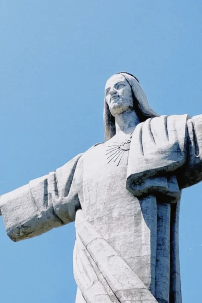 Close-up of the Cristo Rei statue with arms outstretched against a clear blue sky, a highlight stop on the Self-Guided E-Bike Road Tour, an experience by MADcycle.