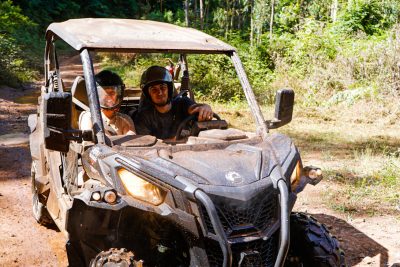 Two people driving a muddy off-road buggy through a forest trail on Madeira Islandl, during an adventure buggy tour by Buggy Funtrip Madeira