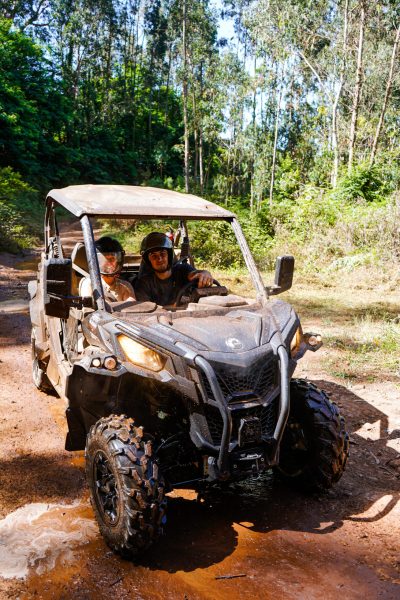 Two people driving a muddy off-road buggy through a forest trail on Madeira Islandl, during an adventure buggy tour by Buggy Funtrip Madeira