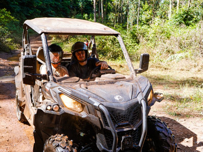 Two people driving a muddy off-road buggy through a forest trail on Madeira Islandl, during an adventure buggy tour by Buggy Funtrip Madeira