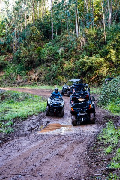 Convoy of buggies and an ATV driving along a muddy forest trail, passing a water puddle during an off-road tour in Madeira, during an adventure buggy tour by Buggy Funtrip Madeira.