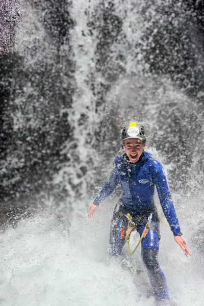 A thrilled canyoneer jumps joyfully into a cascading waterfall during an Intermediate Level 2 canyoning experience in Ribeira do Cidrão, Nuns Valley, with Go Explore Madeira.
