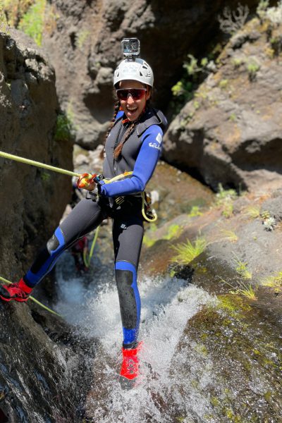 A grinning canyoneer with GoPro descends a narrow canyon waterfall in Ribeira do Cidrão, Nuns Valley, on an Intermediate Level 2 canyoning adventure with Go Explore Madeira.