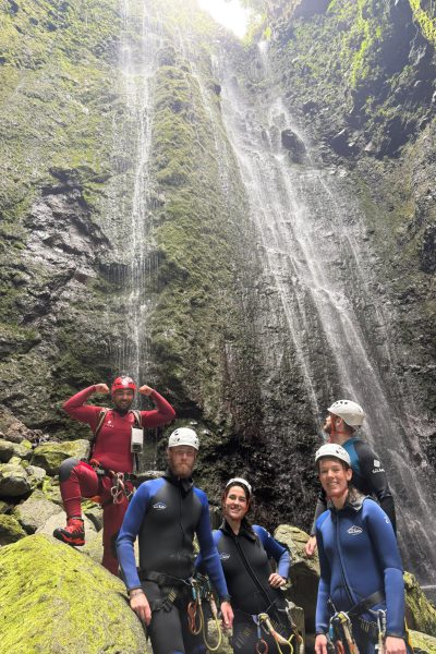 A group of canyoneers poses at the base of a towering waterfall in Ribeira Funda Inferior after an Advanced Level 3 canyoning descent with Go Explore Madeira.