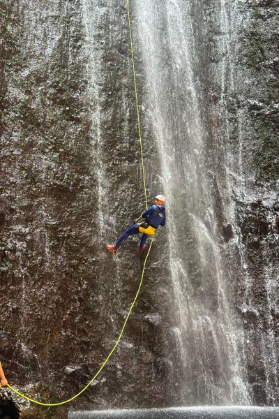 A canyoneer abseils down a vertical waterfall wall in Ribeira Funda Inferior during an Advanced Level 3 canyoning descent with Go Explore Madeira.