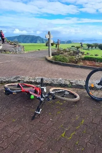 E-bikes resting on a terrace overlooking green fairways and distant mountains at a viewpoint stop on the Levada da Camacha Trail by E-Bike, an experience by Madeira Island Route.