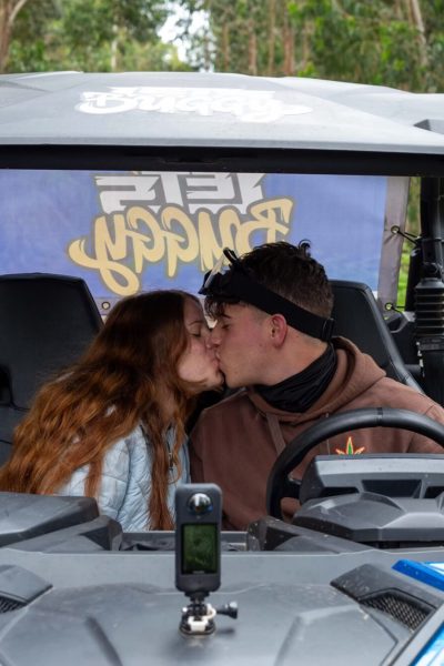 A closeup of a couple kissing each other on a Can Am with the forest in the background, during a Let's Buggy's Trail Thrill experience in Madeira.