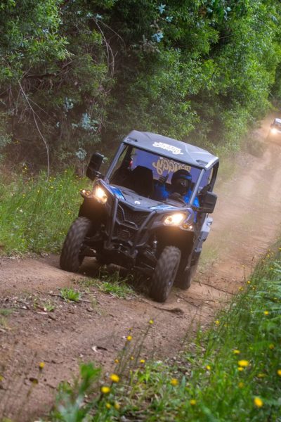 A blue Can-Am buggy leads through a tree-lined dirt path amid lush greenery followed by another one, during Let's Buggy's half day Explorers tour experience in Madeira.