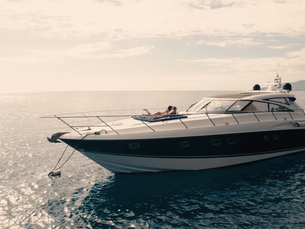 Luxury Madeira Yacht Charter Rental in the sea with two woman sunbathing, near the coast of Madeira, an experience by Luxury Charter Madeira.