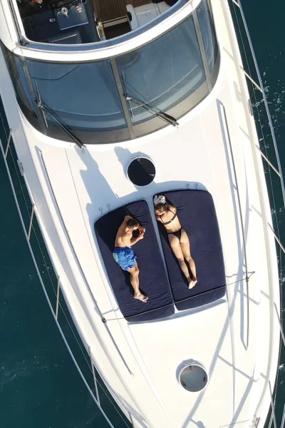 A Drone Top view close up of a couple sunbathing in a Luxury Madeira Yacht Charter Rental in the sea of Madeira, an experience by Luxury Charter Madeira.