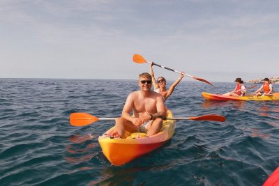 Couple kayaking on the ocean during a Madeira Radical Kayak Funchal Tour, an experience by Madeira Radical, with other participants paddling nearby on the calm blue water.