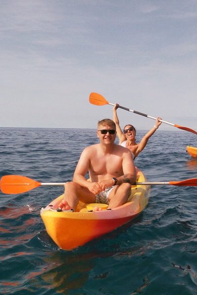 Couple kayaking on the ocean during a Madeira Radical Kayak Funchal Tour, an experience by Madeira Radical, with other participants paddling nearby on the calm blue water.