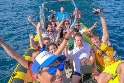 Group enjoying our 4h Day Pack fun in a boat tour at Ponta de São Lourenço, celebrating on a yellow speedboat in front of the iconic sea arch during a boat tour experience by Madeira Sea Emotions.