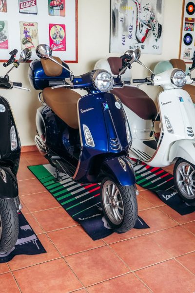 A black,a blue ,a white and Green Vespa Parked inside the headquarters of Vespa Madeira Scooter Rent.