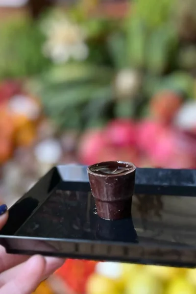 Ginjinha served in a chocolate cup at a colorful Funchal market stall during the Bar hopping and Poncha Workshop, an experience by Wine Tours Madeira.