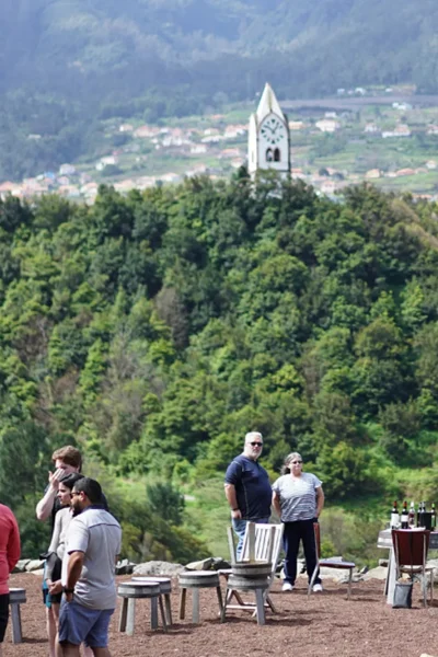 Tour group relaxing outdoors with white church tower and mountains in background, an experience by Wine Tours Madeira