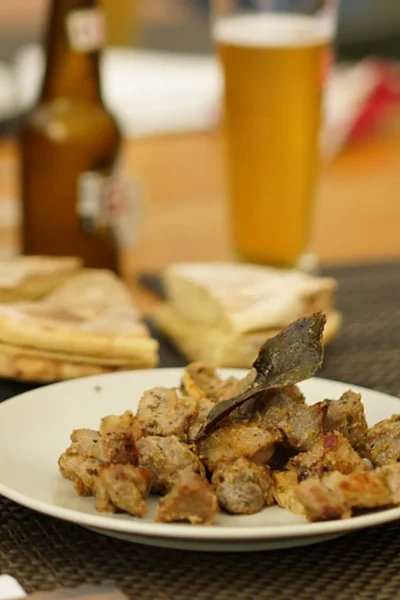 Traditional Madeira snack with grilled carne de vinha d’alhos, bolo do caco bread and cold Coral beer during the Wine and Food Walking Tour in Funchal, an experience by Wine Tours Madeira.